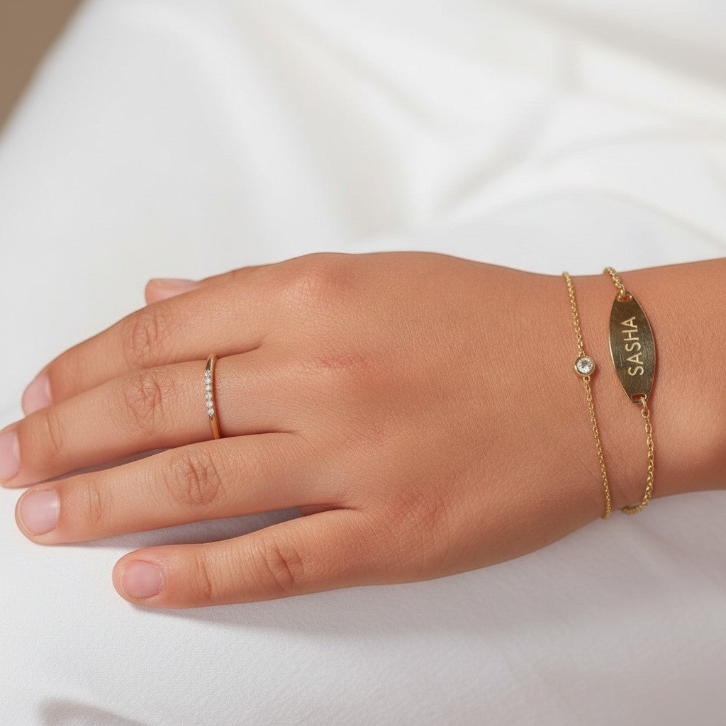 Lotus Diamond kids 14K gold bracelet with bezel-set diamond and personalized oval tag engraved with 'SASHA'.